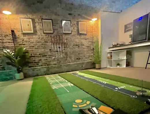 Green-lit bay with the screen and hitting mat at Anytime Golf Suites in Joplin, MO