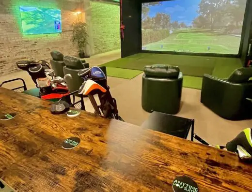 Sim bay with a couch and screen at Anytime Golf Suites in Joplin, MO