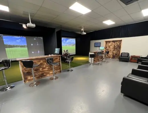 Sim bays with high-top tables at Gopher's Indoor Golf in Westford, MA