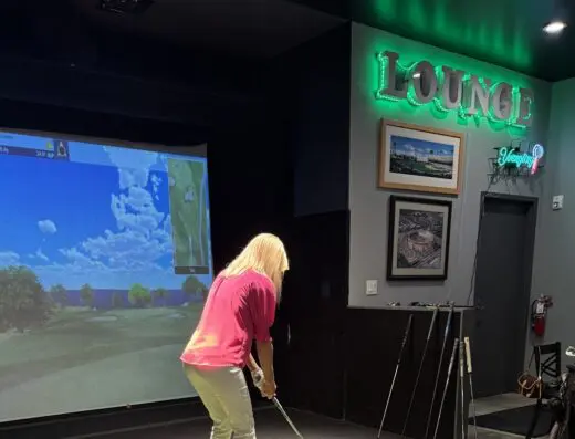 Golfer in a bay hitting into the screen at Rounds Golf & Lounge in Wilmington, NC