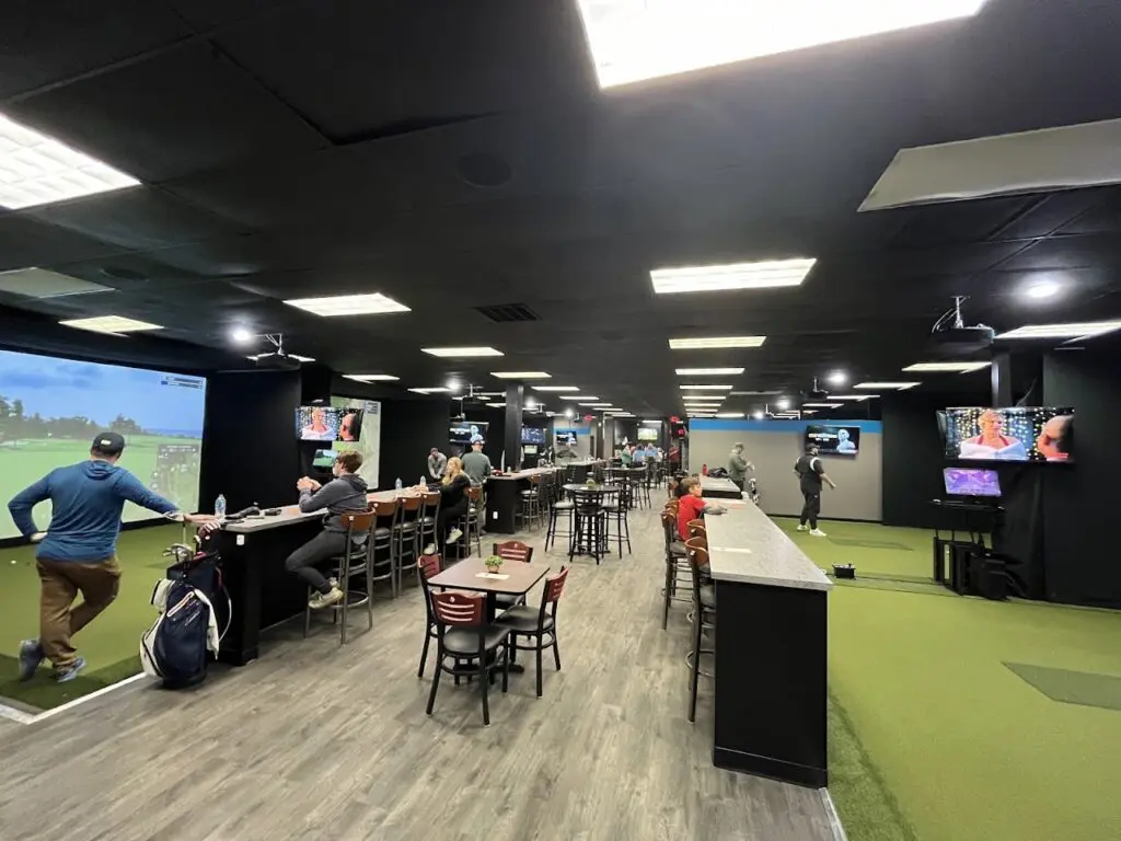 Wide simulator bays and seating inside Swing Space Golf on East Main Street in Columbus, Ohio