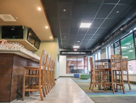 Row of sim bays with high-top tables at X-Golf Portland in Portland, ME