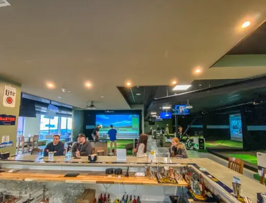 Bar with guests and sim screens, TVs at X-Golf Portland in Portland, ME