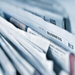 A close-up of a stack of newspapers, with the headline World Business visible, suggesting global business news—perhaps even features on innovations like golf simulators or trends in golf sim technology. The edges of the papers are slightly rumpled.