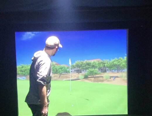 Golfer hitting in a simulator bay at Birdies Indoor Golf & Bar in Oxford, MI