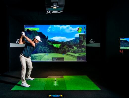 Golfer in a simulator bay at X-Golf Holland in Holland, MI